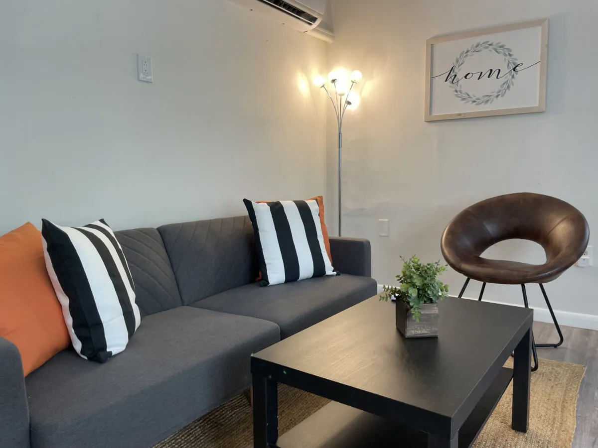 A cozy interior living space featuring a comfortable sofa and armchair arranged around a coffee table, complemented by stylish wall art. The scene invites relaxation after a day of work or exploration, indicating a welcoming retreat for business travelers.